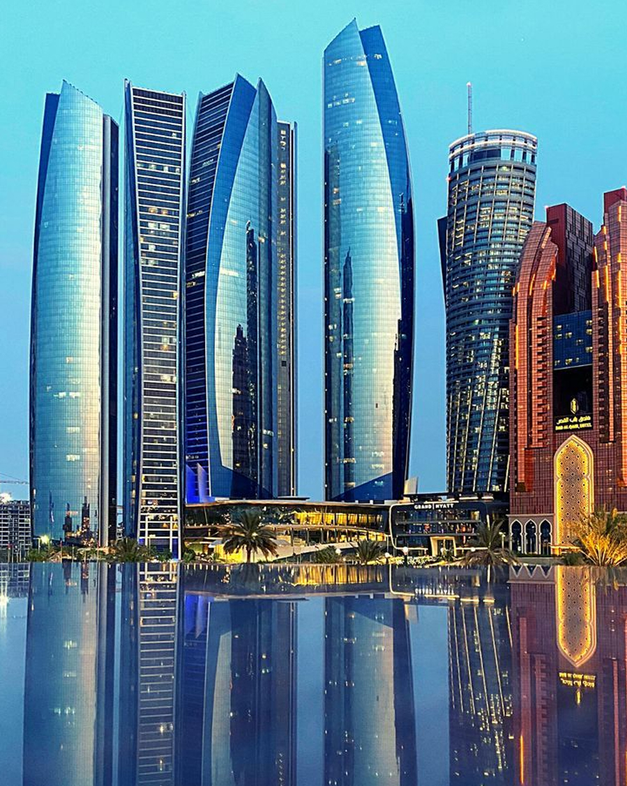 Etihad Towers in Abu Dhabi reflecting on water at dusk, a symbol of global business and luxury travel.