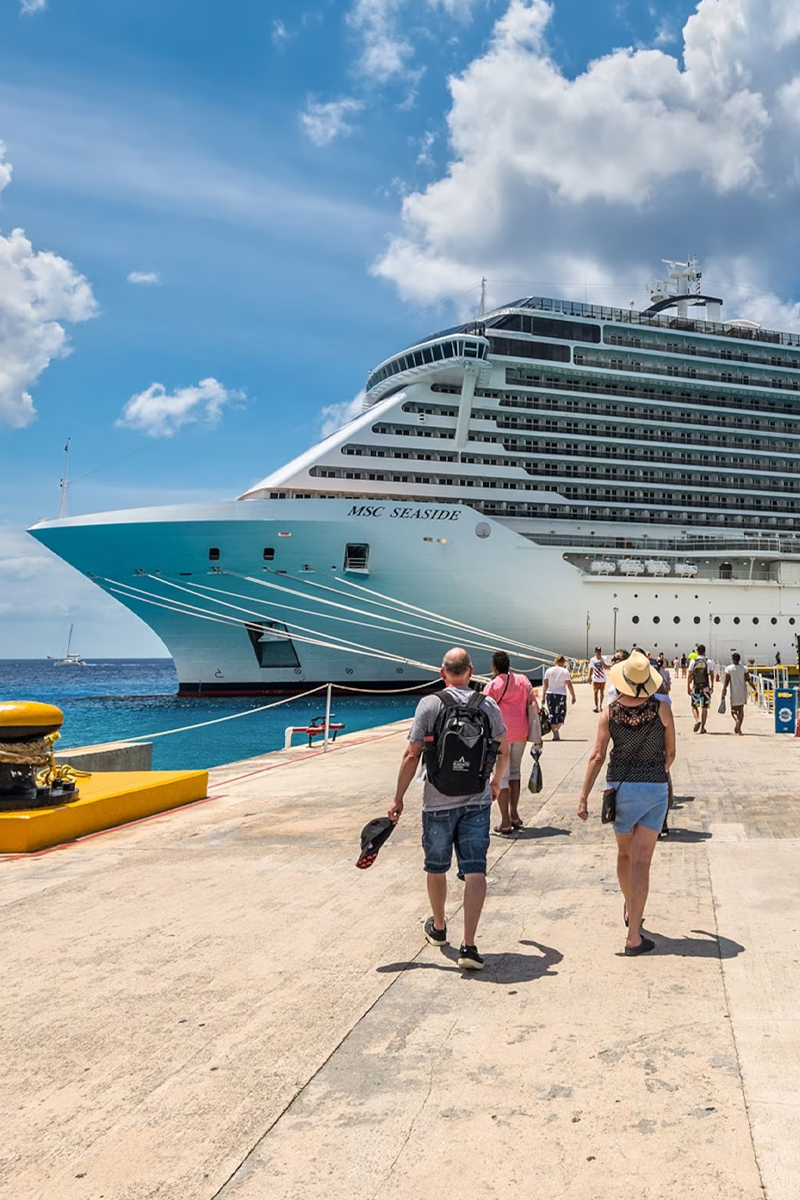 Passengers boarding MSC Seaside cruise ship under a bright blue sky