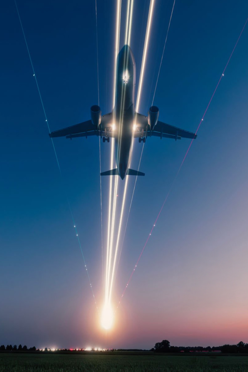 Airplane taking off at night leaving light trails in the sky